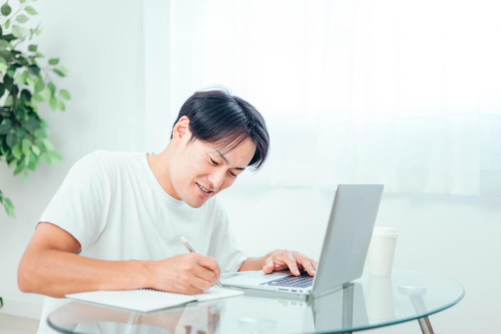 ノートパソコンを使って楽しそうに勉強している男性