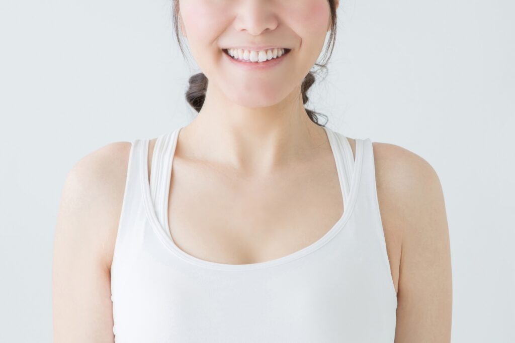 白いタンクトップを着ている女性の口元から胸にかけての画像