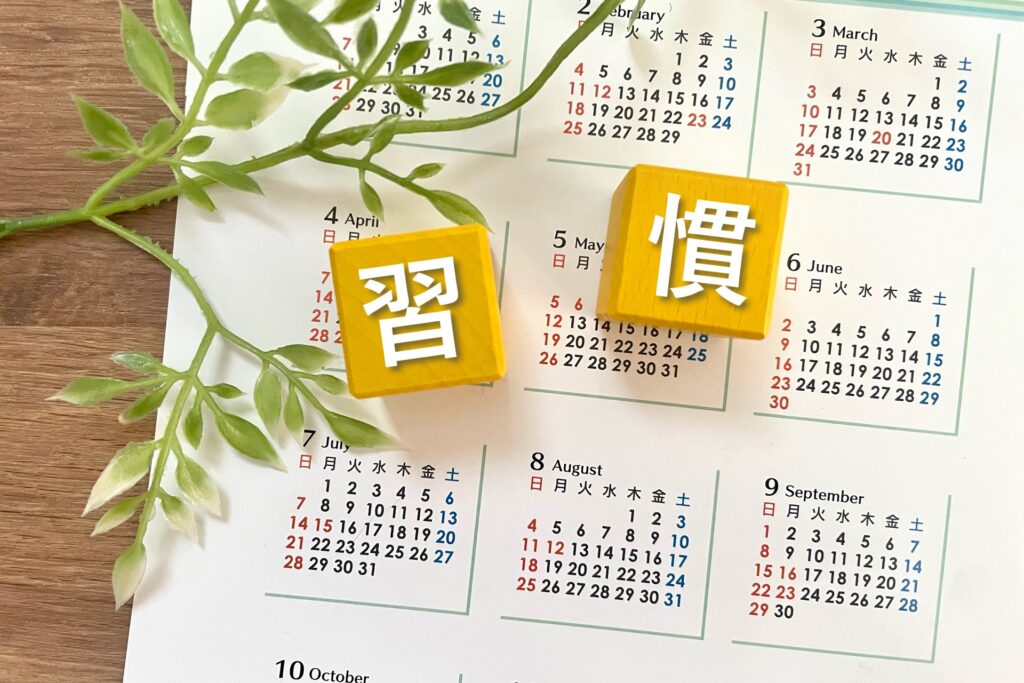 カレンダーの上にある観葉植物と習慣と書いてある黄色い積み木